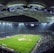 An expansive soccer stadium filled with spectators, illuminated by bright overhead lights, showcasing a well-maintained green field with players scattered across it. The stadium's curved roof and seating areas create a grand and dramatic atmosphere.